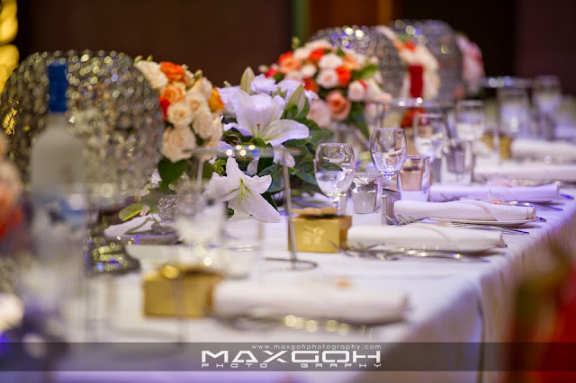 Layered paper cut-out collage of an elegant wedding banquet table with soft floral shapes, wine glasses, and warm candlelight tones in cream and gold